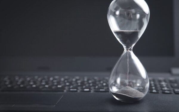 Hourglass with black sand sitting on black laptop keyboard