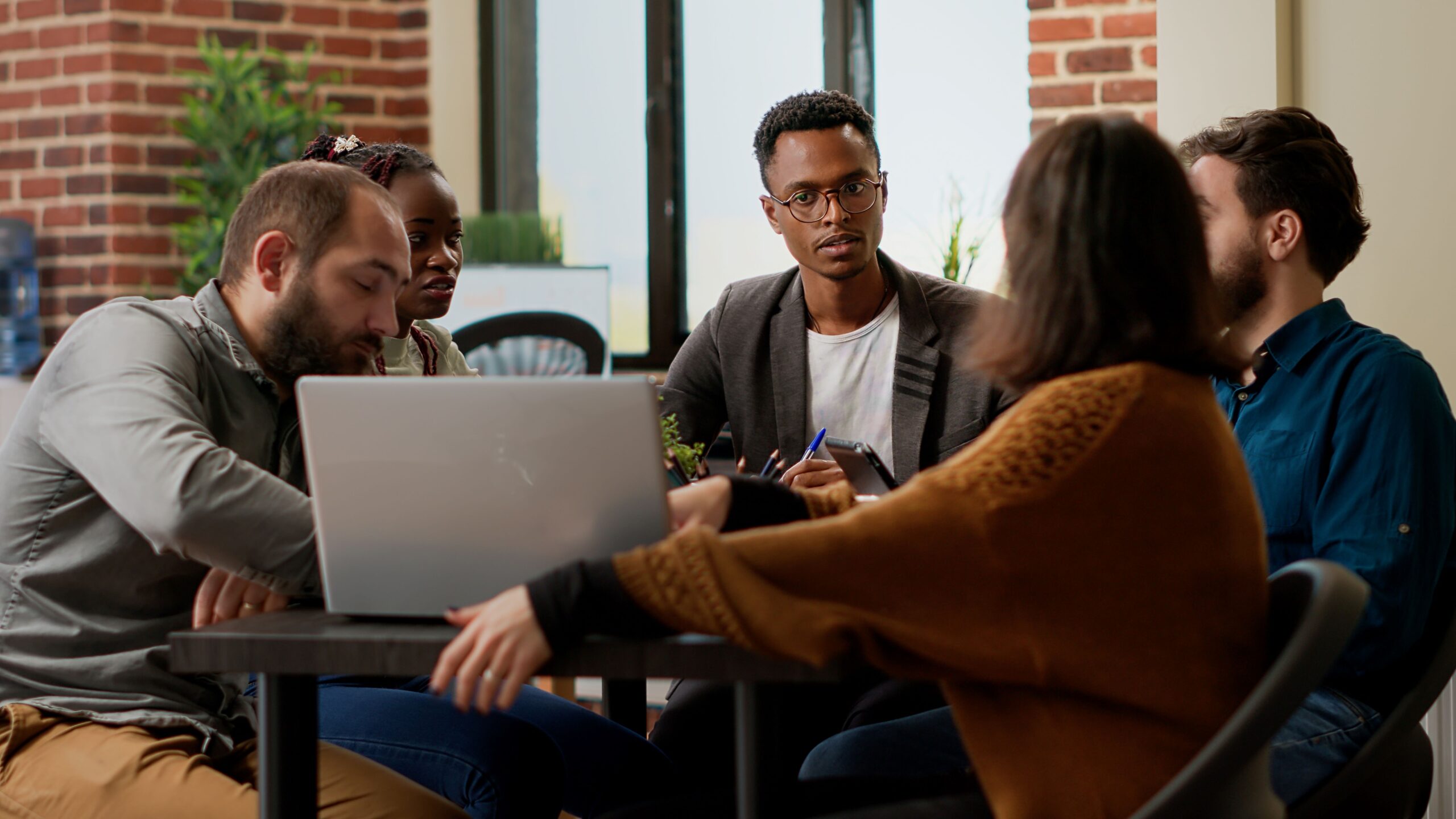 team of 5 casually dressed business coworkers brainstorming ideas at an office