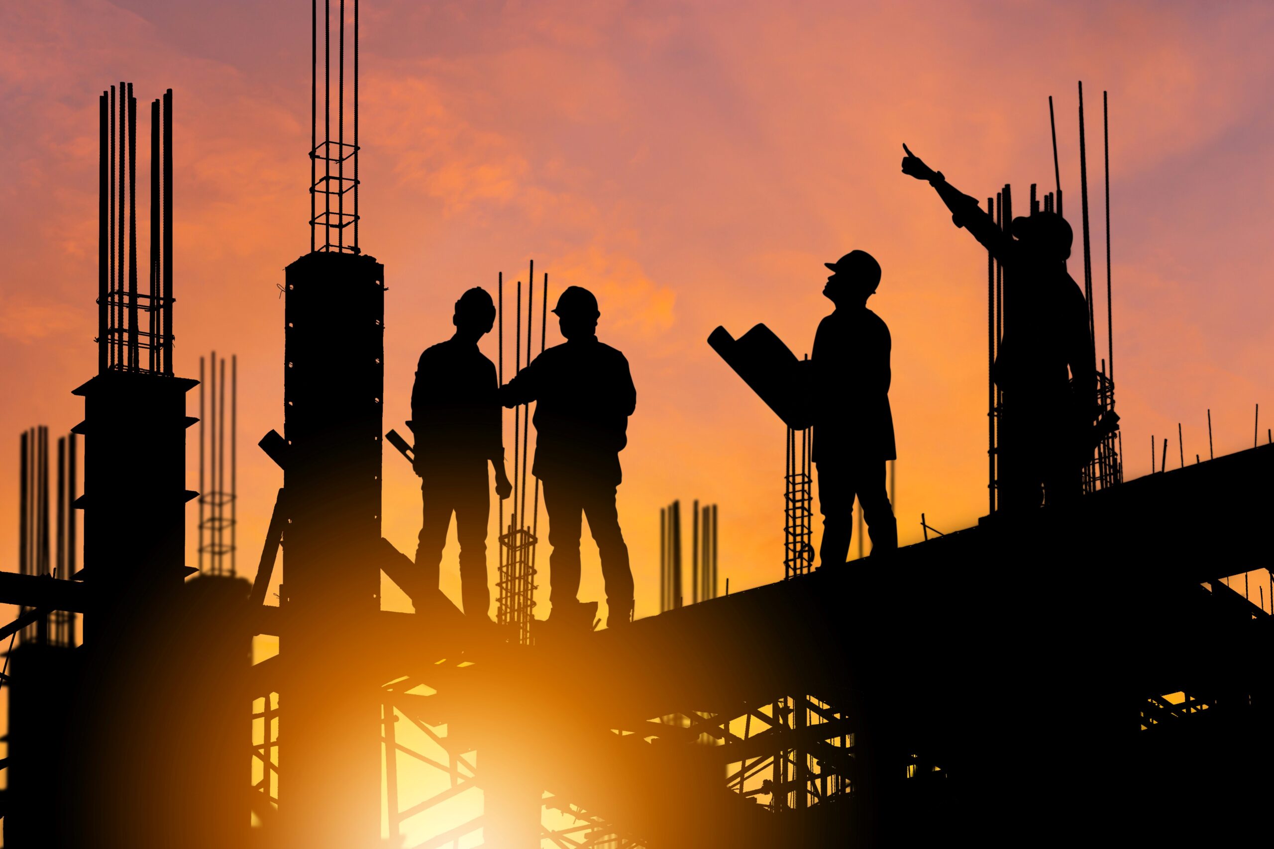 Silhouettes of 4 construction workers against a sunset