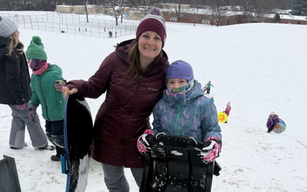 Woman holding sled with daughter